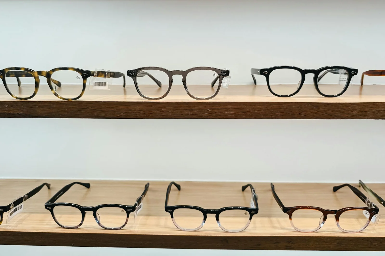 Showcase of stylish eyeglasses on wooden shelves, highlighting modern eyewear design and clear vision.